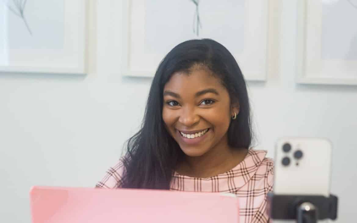 Mikayla Taylor, SEO strategist for women entrepreneurs, typing on pink macbook at desk