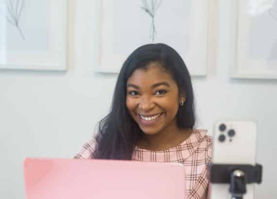 Mikayla Taylor, SEO strategist for women entrepreneurs, typing on pink macbook at desk